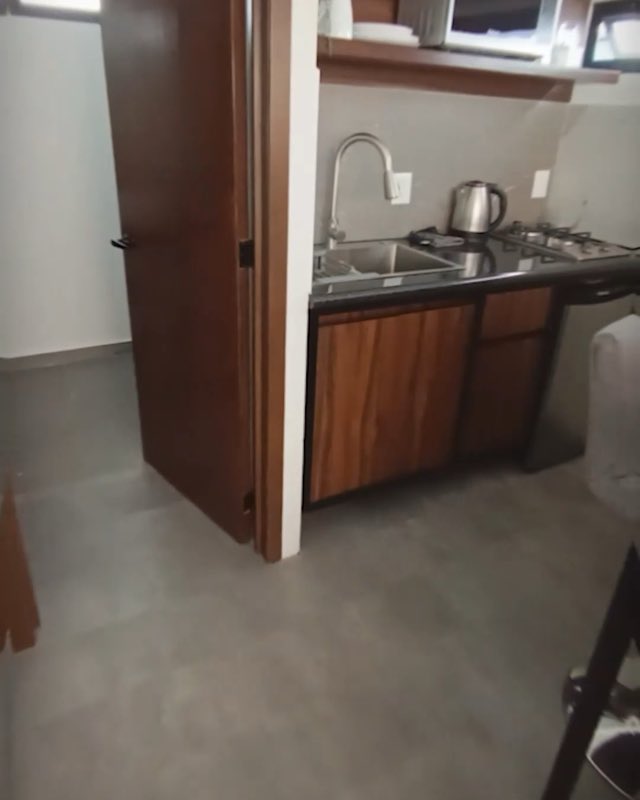 Cocineta con tarja, parrilla y gabinetes de madera dentro de una minicasa terminada