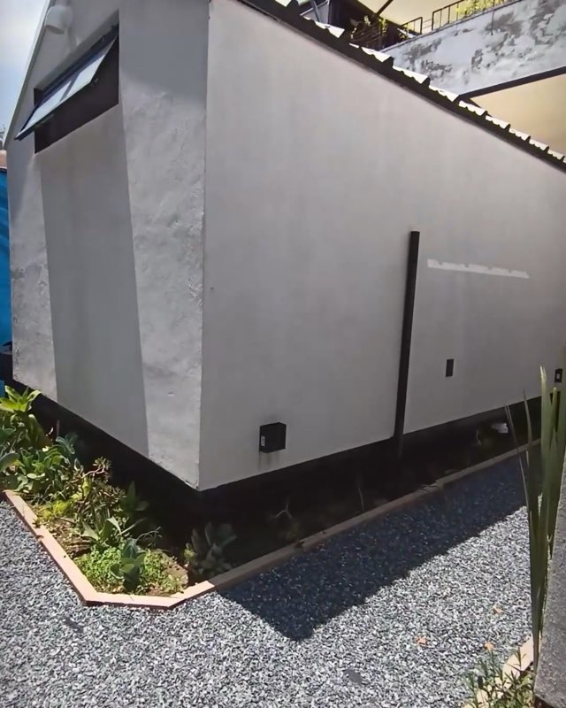 Exterior de una minicasa Xhantli terminada, con acabado blanco y jardinera de grava