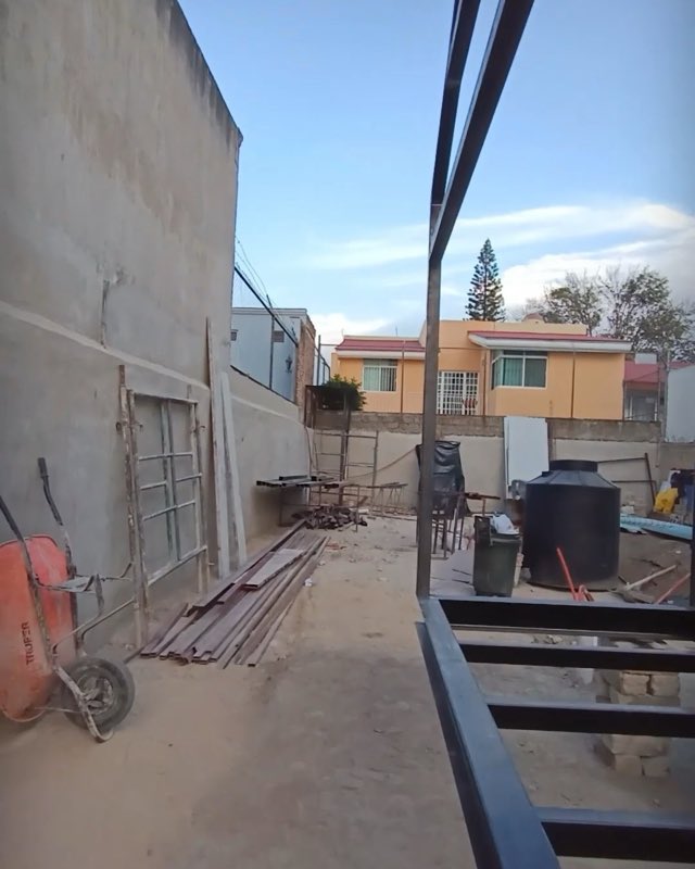Base metálica de una minicasa en el patio del taller, con materiales de obra